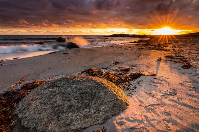 Sunset over a beach with waves and rocks
