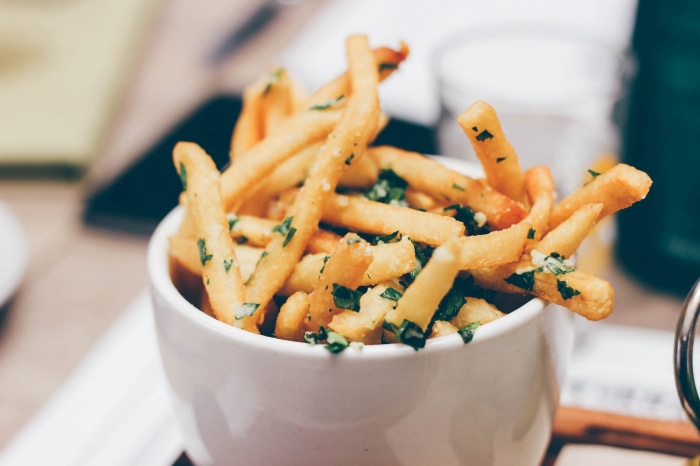French fries with parsley in a white bowl