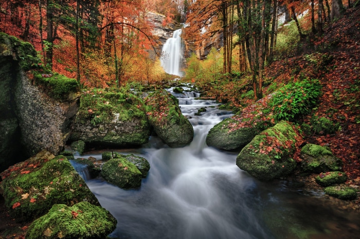 Waterfall in autumn forest with mossy rocks