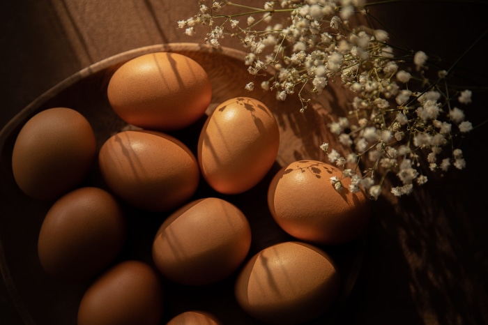 Brown eggs in a wooden bowl with flowers