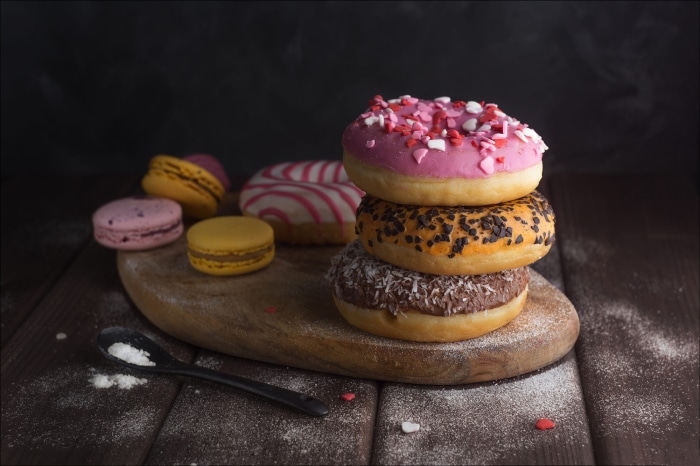 Stack of donuts and macarons on a wooden board