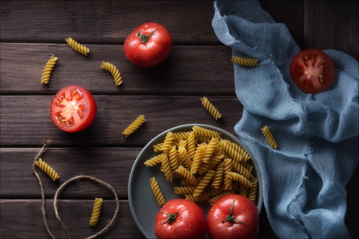 Fusilli pasta and tomatoes on a wooden table