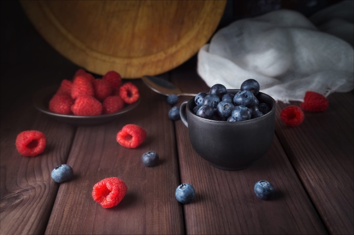 Raspberries and blueberries in a dark still life