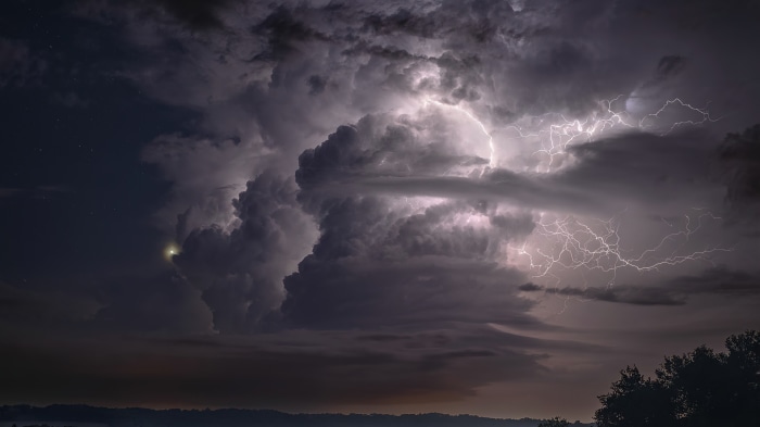 Lightning strikes through dark storm clouds