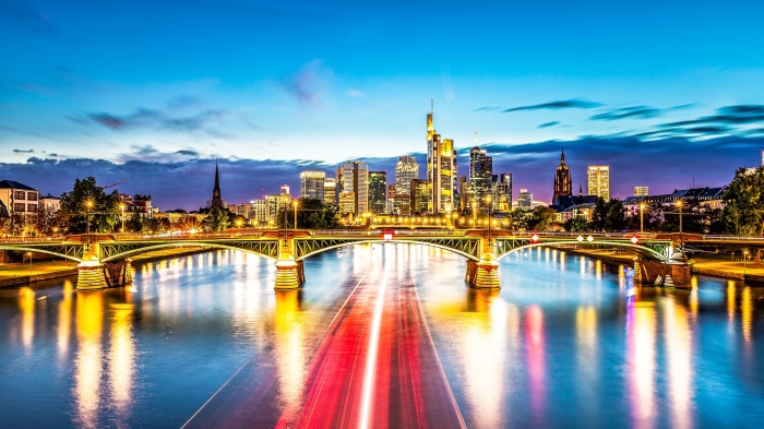 Frankfurt skyline and bridge over river at dusk