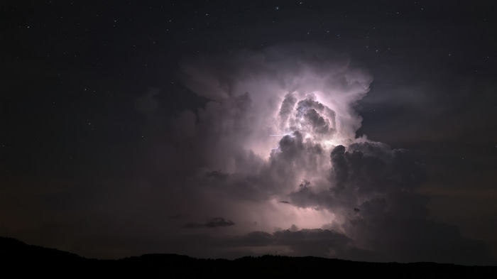 Lightning storm over dark landscape at night