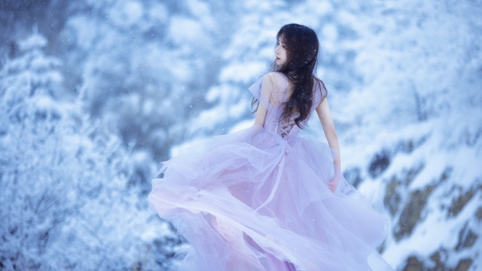 Asian woman in a purple dress in a snowy forest