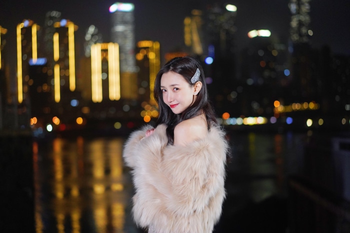 Woman in fur coat at night with city skyline