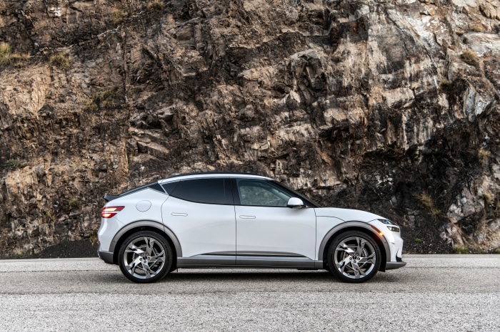 White Genesis GV60 parked on a road with rocky mountain background