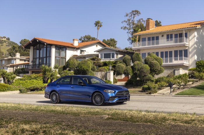 Blue Mercedes-Benz C 300 driving on a road with houses