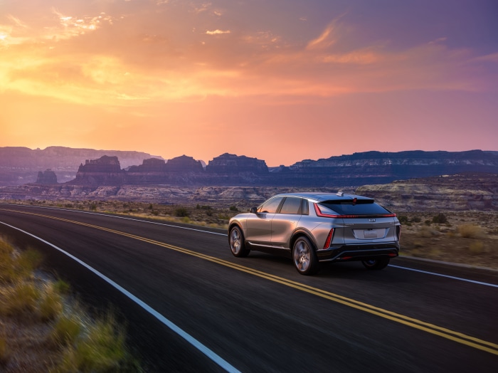 Cadillac Lyriq driving on a desert road at sunset
