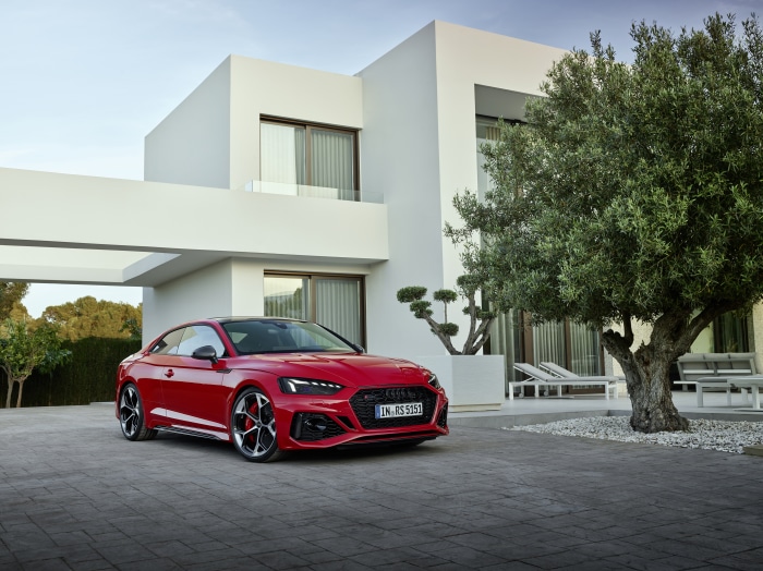 Red Audi RS5 parked in front of a modern white house