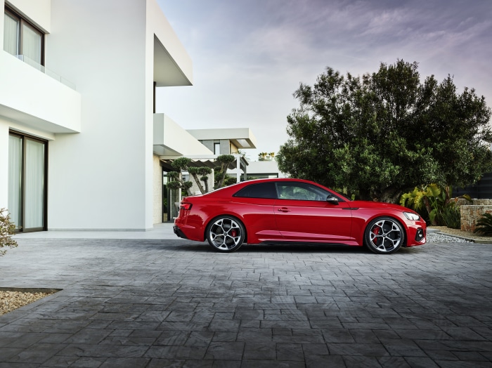 Red Audi RS5 parked by a modern white house
