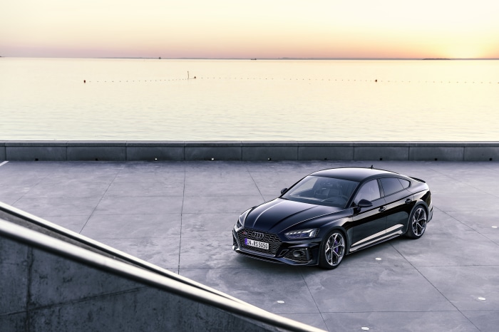 Black Audi RS5 parked by the water at sunset
