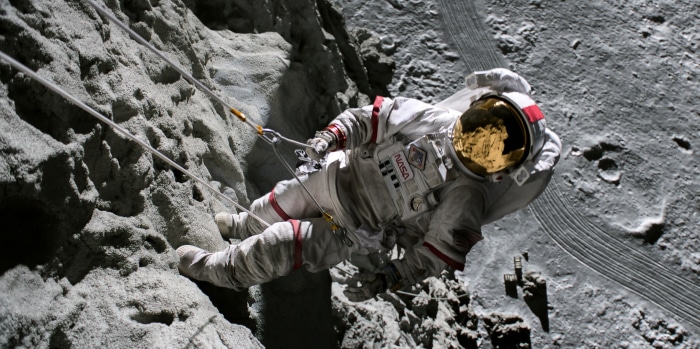 Astronaut rappelling down a rocky surface on the Moon