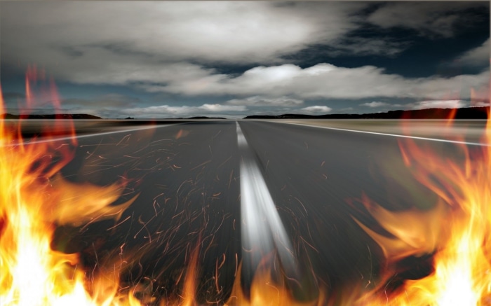 Road engulfed in flames under a cloudy sky