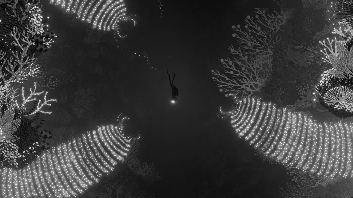 Diver in dark ocean with glowing coral