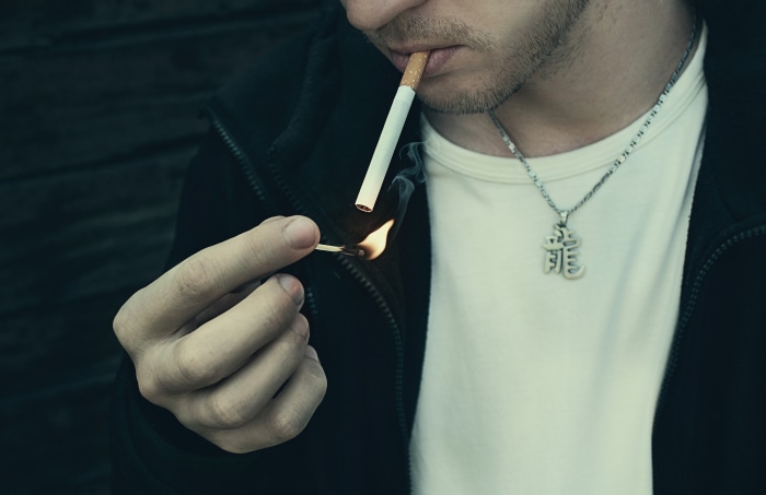 Man lighting a cigarette with a match