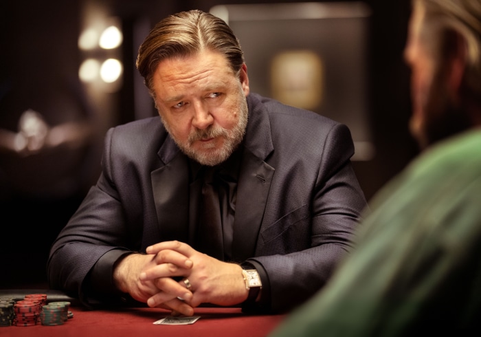 Russell Crowe in a dark suit at a poker table