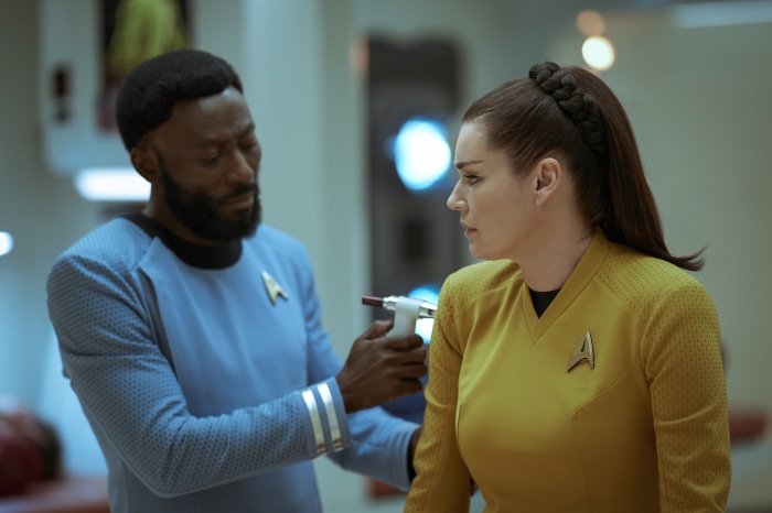 Man in Star Trek uniform examines woman in uniform