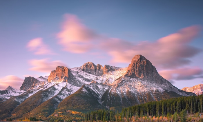 Snow-capped mountains at sunrise with pink clouds