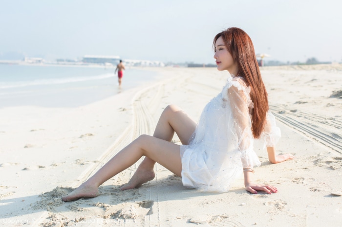 Model Sitting on Sandy Beach in