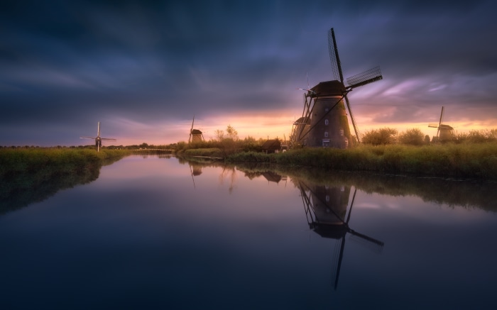 Windmills reflected in a canal at sunset in the Netherlands