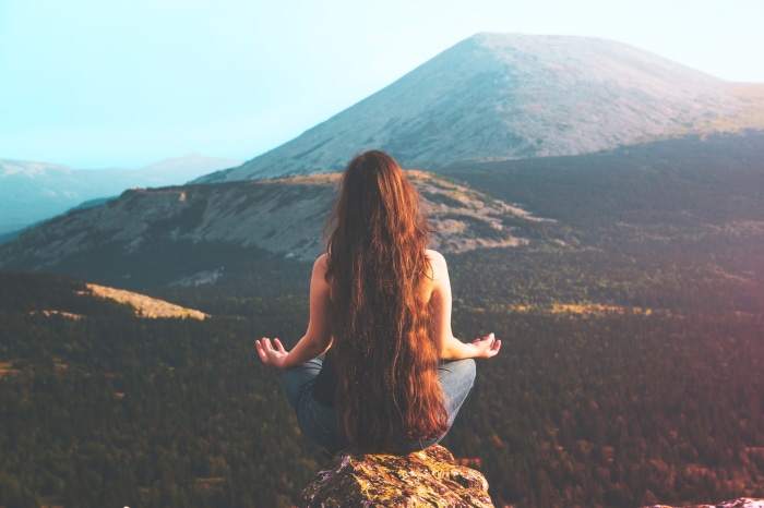 Brunette meditating on a mountain top 4K