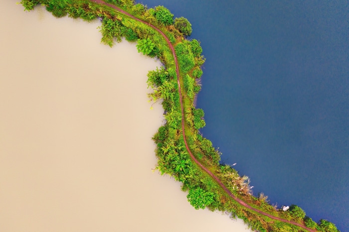 Aerial view of two contrasting bodies of water separated by a green path