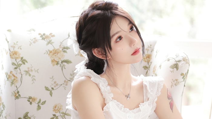 Asian woman with dark hair sitting on a floral armchair