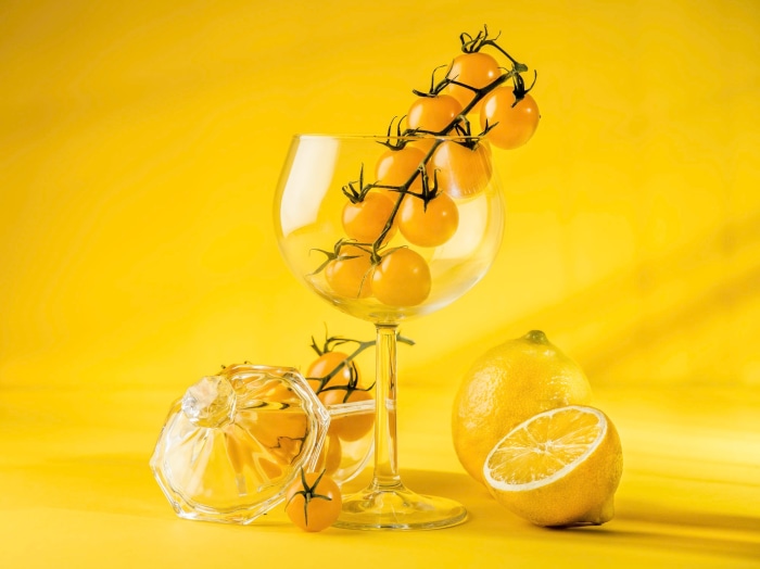 Yellow tomatoes and lemon on a yellow background