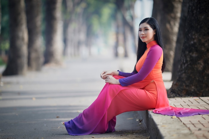 Asian woman in colorful dress sitting outdoors