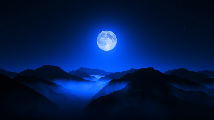 Full moon over a misty mountain valley at night
