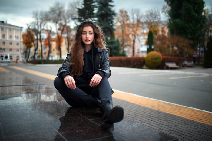 Young woman in black leather jacket sitting on marble