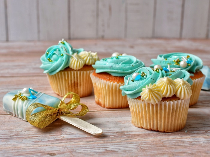Cupcakes and a decorated cake pop on a wooden table