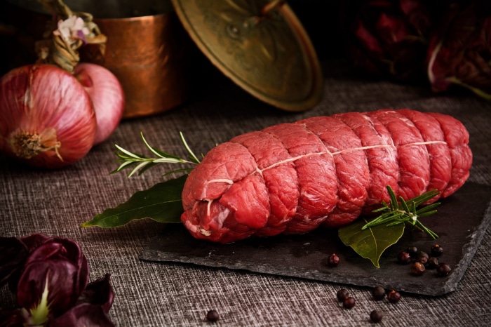 Raw beef roast tied with twine on a slate board