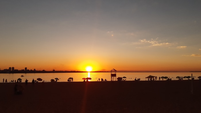 Sunset over a beach with people and a city skyline
