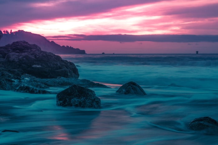 Ocean waves crashing on rocks at sunset