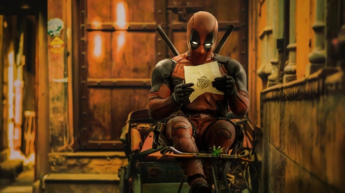 Deadpool sitting and reading a letter