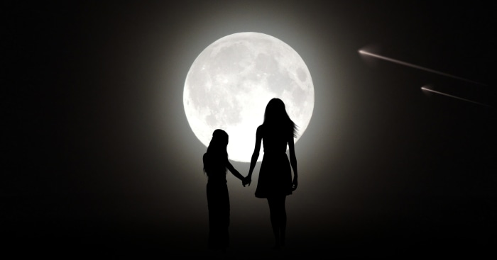 Mother and daughter holding hands under the moon