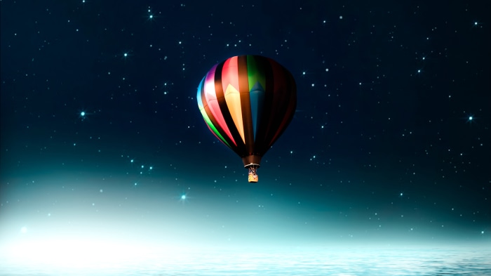 Hot air balloon in a starry night sky over water