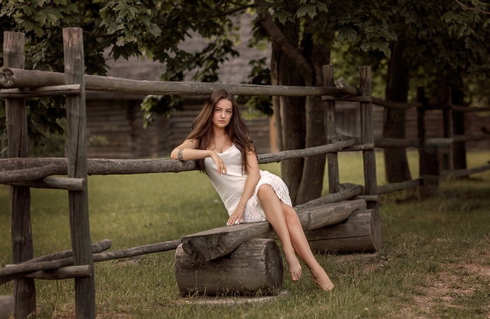 Woman in white dress sitting on a wooden fence
