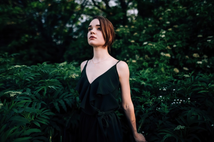 Woman in black dress standing in foliage