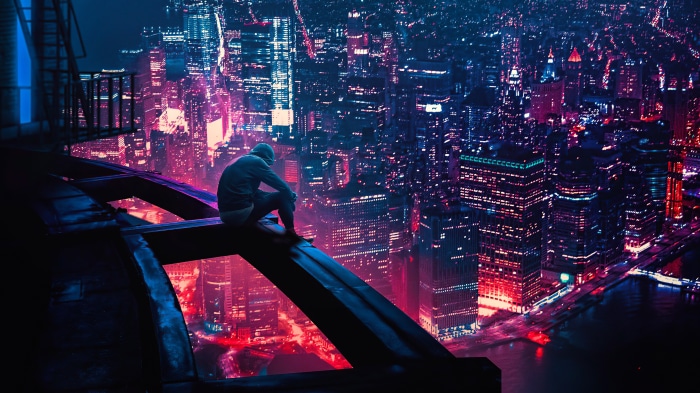 Man on skyscraper overlooking neon city at night
