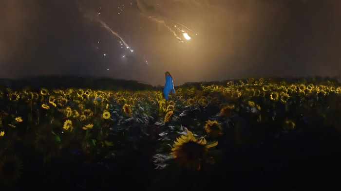 Woman in blue standing in a sunflower field at night