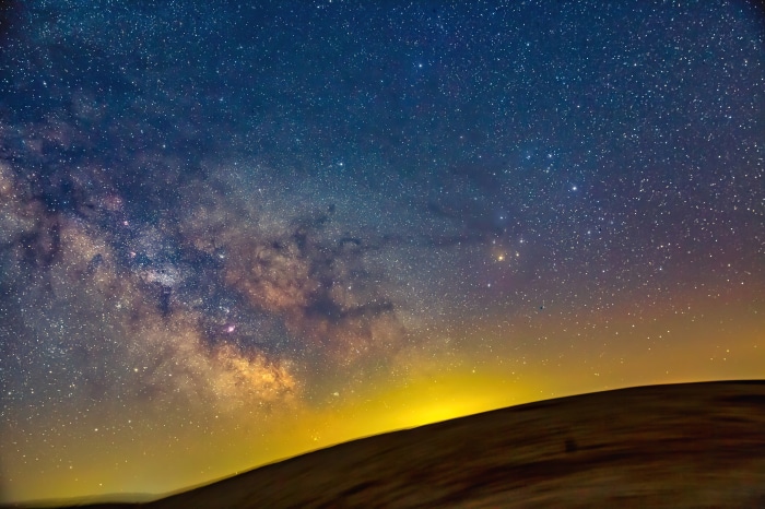 Milky Way galaxy over a dark landscape