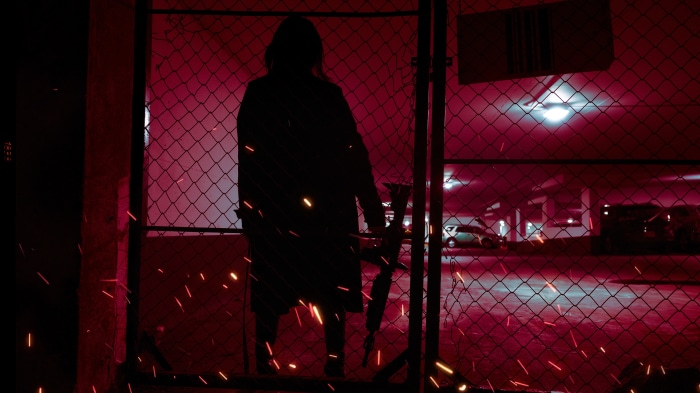 Silhouette of a person with a weapon behind a fence