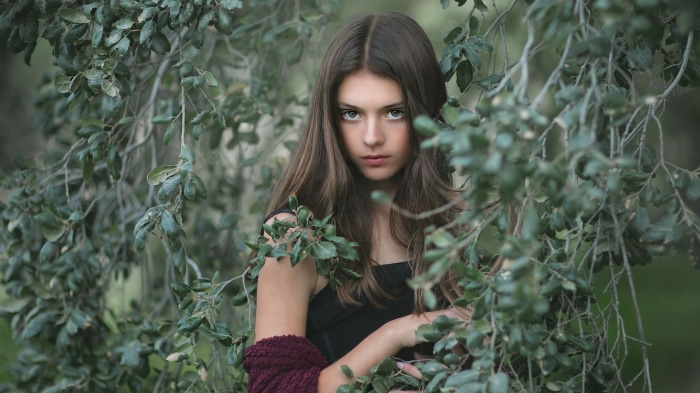 Young girl among green leaves