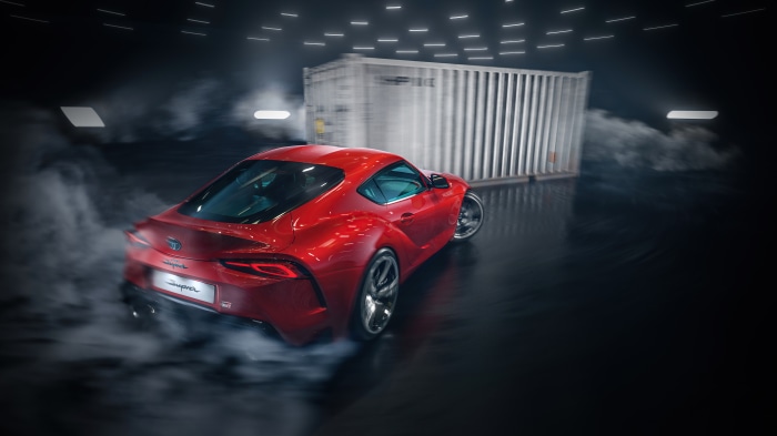 Red Toyota Supra drifting near shipping container