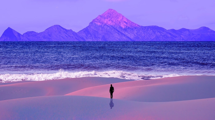 Man on a purple beach with mountains and ocean